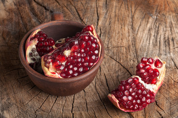 pomegranate slices on an old wooden background, pomegranate pieces in a clay cup