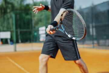 Close Up of Man Playing Tennis At Court And Beating The Ball With a Racket. Player is Hitting Ball...