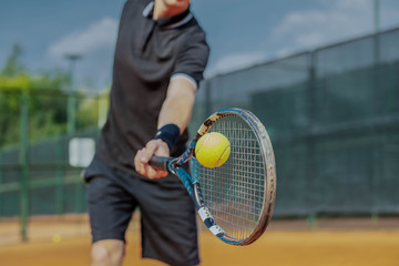 Close Up of Man Playing Tennis At Court And Beating The Ball With a Racket. Player is Hitting Ball With Racket While Playing Match