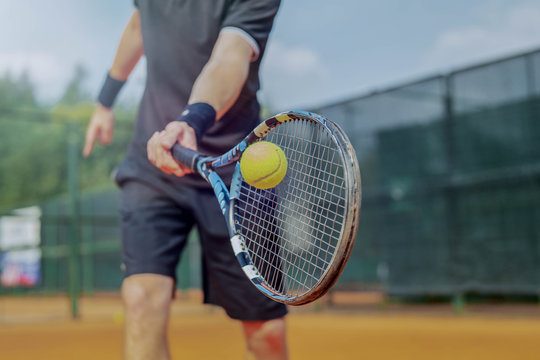 Close Up of Man Playing Tennis At Court And Beating The Ball With a Racket. Player is Hitting Ball With Racket While Playing Match