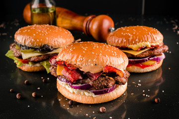 row of three burgers on a dark background
