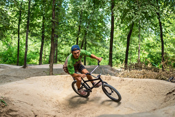 A bmx cyclist makes a sharp turn on a forest trail. Extreme cycling.