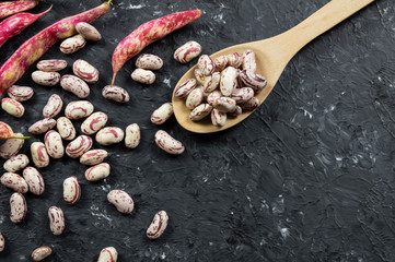 Harvested uncooked dried roman beans with raw pod plant on rustic background, heap of legume kidney bean concept