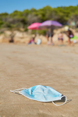 Fototapeta na wymiar used surgical mask thrown on the sand of a beach