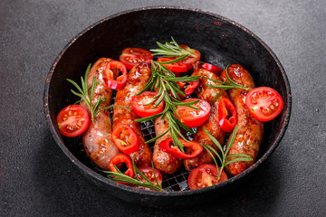 Grilled sausages with vegetables and spices on black background