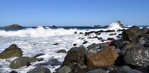 Sea foam and black volcanic rocks on the shore