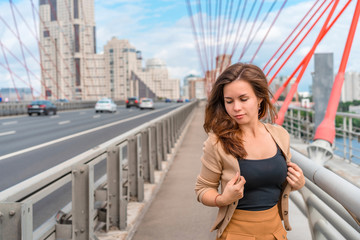 Fototapeta premium A young woman with long hair stands with a view of the picturesque red bridge in Moscow