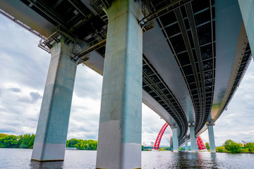 Picturesque red bridge over the river in Moscow, photo taken under the bridge with metal holding beams