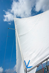 Mastro de veleiro com vela inflada pelo vento em dia ensolarado. Barco navegando