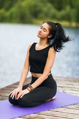 Fototapeta na wymiar Young woman in sportswear sits on the carpet and rests during yoga class