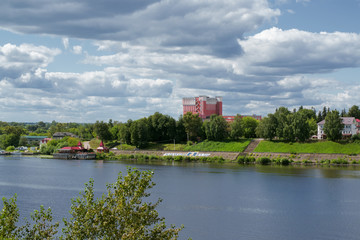 Fototapeta premium Kimry, Tver Region, Russia - August 19, 2020: View of the left bank of the small town Kimry from the bridge. The building of the theater and the embankment on a sunny day