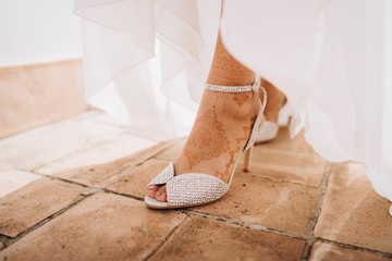 Indian brides mehendi on legs. female foot with high-heeled shoes with mehendi. bride with mehndi...
