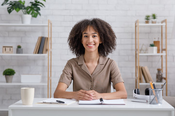 Distant learning language. Smiling teacher sits at table, looks at camera and communicates with...