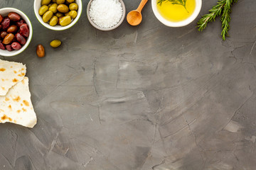 Top view of olives, olive oil, bread on grey table top view copy space