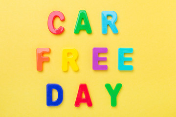 Multicolored text Car Free Day on yellow background. Concept of international car free day on September 22. Top view