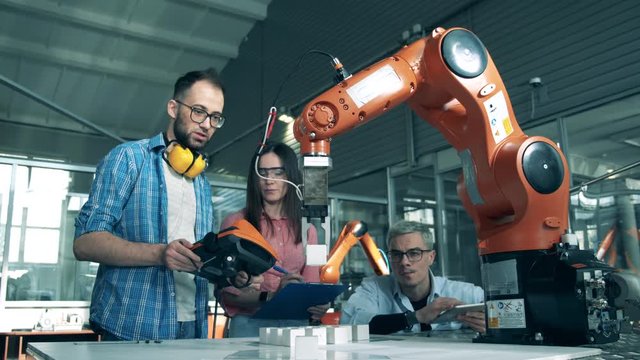 People control robotic arm with tablets. Innovation, hi-tech education, science studying concept.