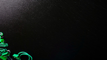 Office / Büro Collage / Hintergrund Bürosortiment auf schwarzem Hintergrund mit Gummiband, Reißzwecken, Büroklammern, Binder-Clips und Freiraum für ihren Text (Copy Text) licht von oben links