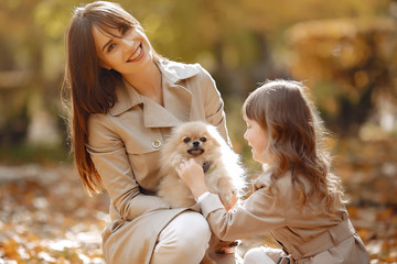 Fashionable mother with daughter. Family in a autumn park. Family with a dog.