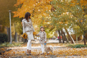 Fototapeta premium Fashionable mother with daughter. Family in a autumn park. Family with a dog.