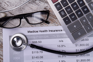 Medical health insurance concept. Accountant's report with stetshoscope, calculator and glasses.