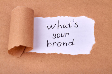 Concept of discovering your brand. Uncovered beige paper and what's your brand slogan on revealed white piece of paper.