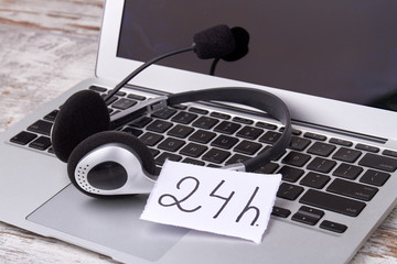 Concept of 24/7 hotline. Headset with laptop of helpdesk support employee.