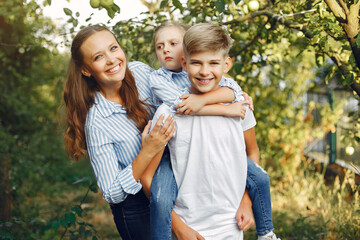 Family in a park. Children near apple tree. Woman in a blue shirt