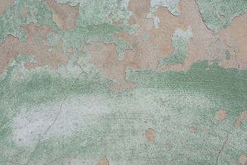 green cracked texture of plaster, with elements of rubbed gray paint. The pastel tone of a textured street wall. Crack in the wall, multiple holes in the old green plaster