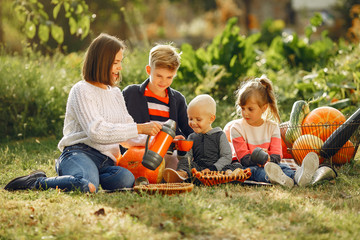 Family in a garden. People with pumpkins. Mother with three kids