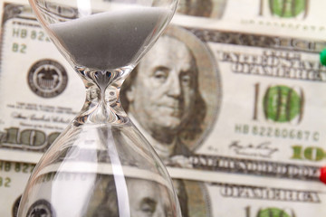 Time is money concept. Retro sandglass on money background. One hundred dollars in one bill.