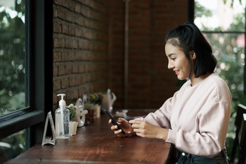 Portrait of an Asian teenage woman chill out and make payment through credit card and smart phone in the cafe. Stock photo.