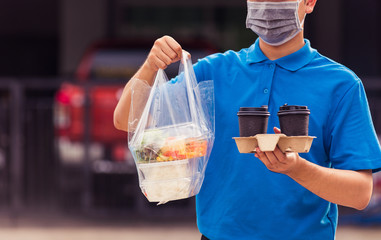 Asian young delivery man in blue uniform wearing face mask making grocery service giving rice food boxes plastic bags and coffee at front house under pandemic coronavirus, Back to new normal concept