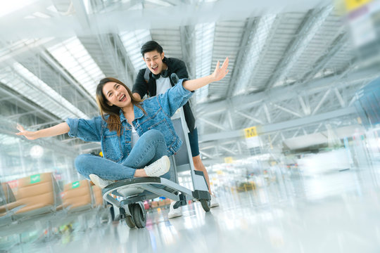 attractive Young Asian tourist couple excited together for the trip girlfriend sitting and cheering on baggage trolley or luggage trolley Holiday vacation safety traveling abroad ideas concept