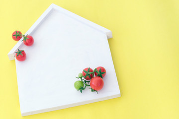 Homegrown concept: cherry tomatoes on white house wooden blank empty space on bright yellow...
