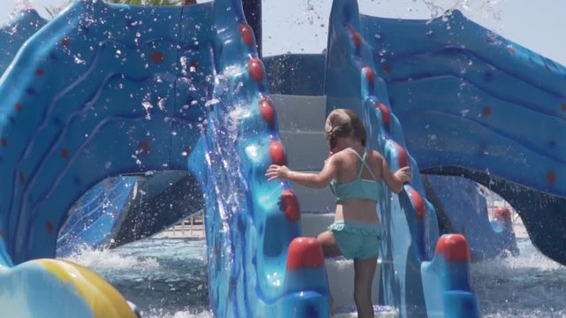 A little girl in a swimsuit climbs a children's water slide in a hotel in Turkey.