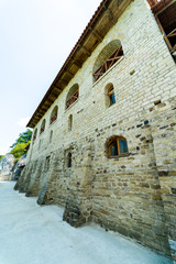 Fototapeta premium Old wall with peeling paint. Scratched stained plaster and closed windows. View from below.