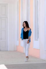 Fototapeta na wymiar Beautiful girl walking in light hall with high celling. Girt in white jeans and blue shirt. Full length photo.