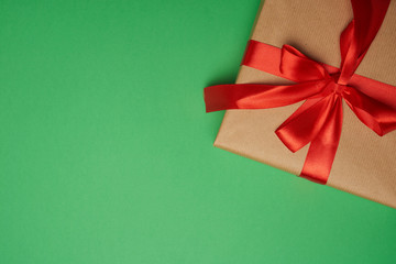 rectangular box wrapped in brown paper and tied with a silk red ribbon with a bow