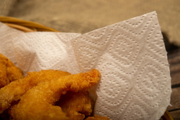 Atlantic shrimps fried in batter on a white paper napkin in a wicker basket. Close up.