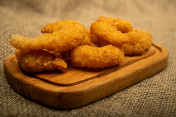 Atlantic prawns fried in batter on a wooden serving Board. Close up.