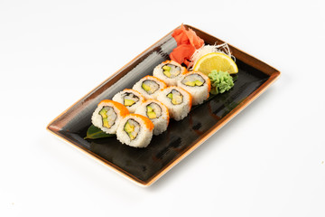 A portion of maki sushi with an assortment of Japanese side dishes in a rectangular ceramic plate on a white plate.