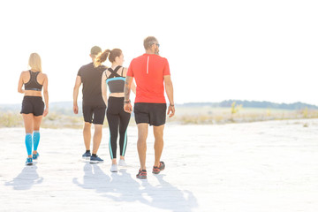 Group of four runners walk on sandy desert land