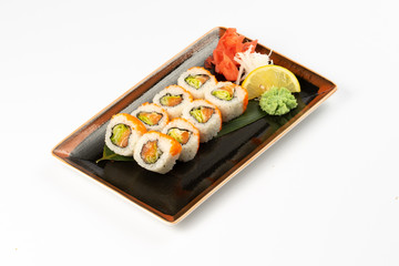 A portion of maki sushi with an assortment of Japanese side dishes in a rectangular ceramic plate on a white plate.