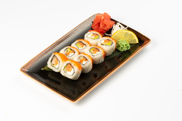 A portion of maki sushi with an assortment of Japanese side dishes in a rectangular ceramic plate on a white plate.