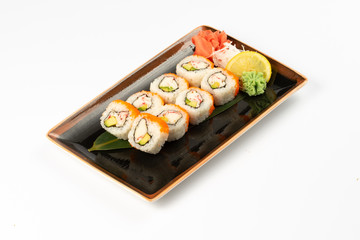 A portion of maki sushi with an assortment of Japanese side dishes in a rectangular ceramic plate on a white plate.