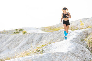 Young woman running on trail path through hills