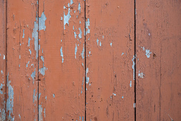 Texture of boards with cracked brown paint. Wooden wall with peeling paint. The boards are installed vertically and painted with brown paint. Texture of an old wall.