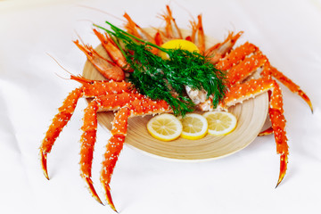 Red king crab and shrimp on a plate with lemon and dill. White background