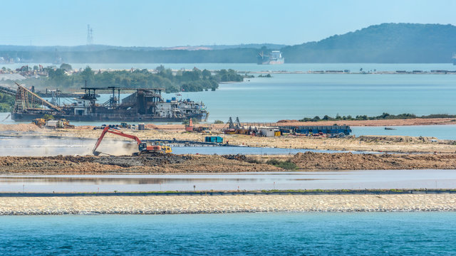 Self-propelled sand carrier barges, lorry, backhoe and other land moving machinery perform ground improvement works to increase soil strength on the development site.