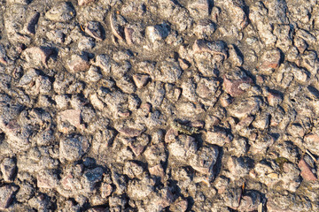Brown texture with stones. Old wall made of natural stone. Cemented uneven stones, earth and moss. Texture of an old wall.